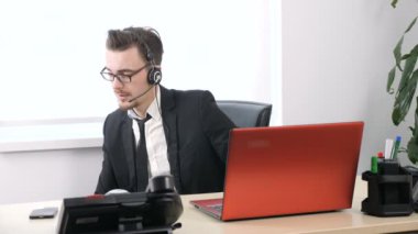 Dışarı içinde belgili tanımlık yazıhane, elbiseli adam çalışır bir egzersiz için pazı ofiste oturan ve yanındaki kırmızı leptop kulaklıktaki konuşma sırasında 60 fps