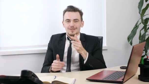 Junger Geschäftsmann im Anzug sitzt im Büro und verdeckt seinen Mund mit den Händen, Schweigezeichen. 60 fps — Stockvideo