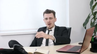 Office ve esneme 60 fps oturan takım elbiseli genç yorgun işadamı