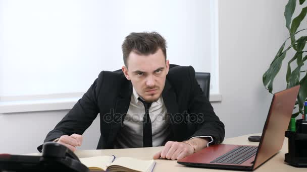 Giovane uomo d'affari arrabbiato in giacca e cravatta è seduto in ufficio e mostra No scuotendo la testa, gesto 60 fps — Video Stock