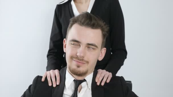 Obtěžování. Ženské ruce masírují ramena mladý podnikatel v obleku. Šťastný, úspěšný šéf s úsměvem 60 fps — Stock video