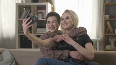 İki genç, güzel kız kanepede oturan ve yapma selfies, lezbiyenler, Lgbt 60 fps