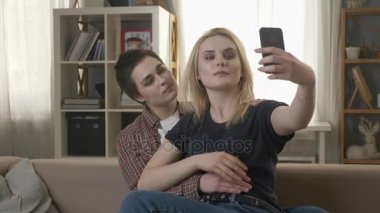 İki genç, güzel kız kanepede oturan ve selfies, lezbiyenler, Lgbt. yapım 60 fps
