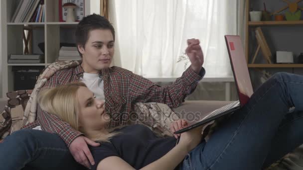 Dvě lesbičky se odpočívá na gauči s laptop, pohodu, lásku, sexuálních menšin, rodinné idyly, mladé 60 fps — Stock video