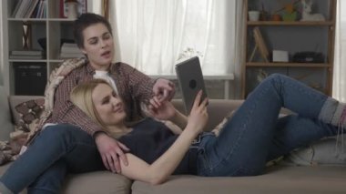 Lezbiyen çift kullanarak tablet bilgisayar, konuşma, Aile İdil, lgbt kanepede oturan 60 fps