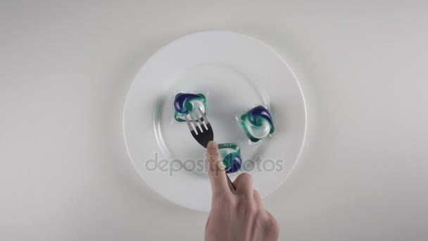 Manos de hombre cortes con un cuchillo lavando vainas de polvo en un plato. Preparación para comer una cápsula con detergente, lavado de vainas de polvo desafío, meme de Internet. 60 fps — Vídeos de Stock