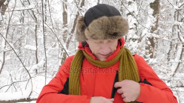 Καυκάσιος ηλικιωμένος βόλτες μέσα στο δάσος του χειμώνα, προσπαθώντας να πιάσει ένα σήμα σε ένα smartphone. Παχύ πυκνό άλσος των δέντρων και τις ρίζες στην στο χιονισμένο δάσος. Πεζοπορία και ταξίδια έννοια 60 fps — Αρχείο Βίντεο