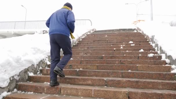 El anciano sube por las escaleras de piedra en invierno. Deportes, cardio. Concepto de vida saludable. 60 fps — Vídeo de stock