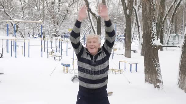 An elderly European man does a morning outdoor warm-up in the winter, Jumping on the Spot Put Your Hands Up and claping. Healthy life concept. 60 fps — Stock Video