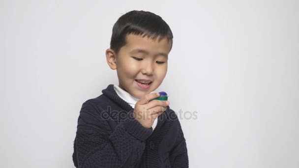 Азіатський дитина тримає пральний порошок pod-о-пліч а облизуючи губи. Дивиться в камеру. Підготовка з'їсти капсулу із застосуванням миючих засобів, Порошок пральний стручки виклик, Інтернет meme. 60 кадрів в секунду — стокове відео