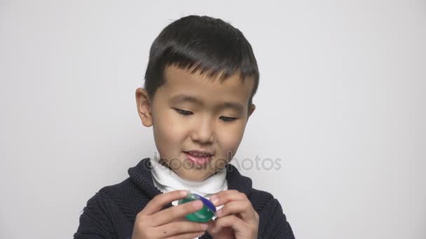 Asiatico bambino tiene il lavaggio cialde in mano e leccare le labbra. Prepararsi a mangiare una capsula con detergente, cialde detergenti sfida, meme internet. 60 fps — Video Stock