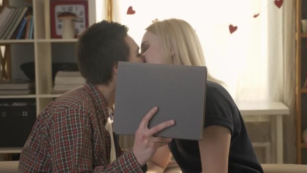 Дві молоді милі лесбіянки обіймаються і пристрасно цілуються і ховаються за великою сірою книгою, милий, коханці, lgbt, дівчата, любов, секс 60 кадрів в секунду — стокове відео