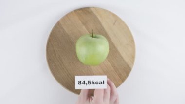 Yeşil elma, erkek el kalori miktarı 60 fps çekim bir tabak bir yeşil elma, en iyi kalori numarasıyla koyar