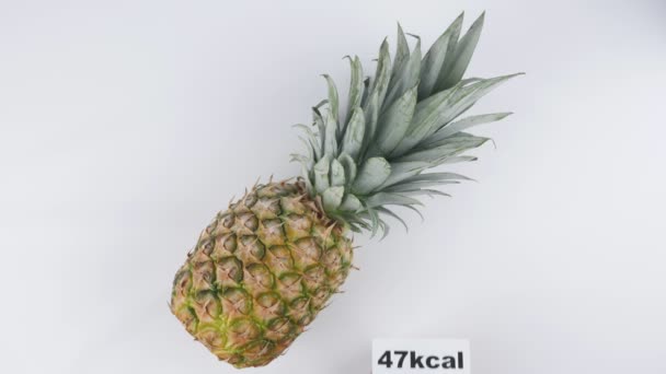 Hoeveelheid calorieën in ananas, mannenhand zet een bord met het aantal calorieën op een ananas, top shot van 60 beelden per seconde — Stockvideo