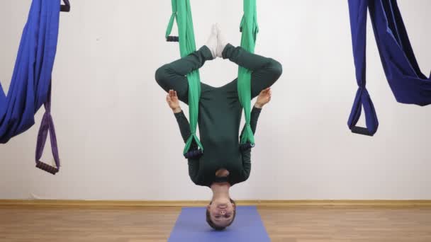 Jonge Kaukasische vrouw maken antigravity vliegen yoga oefeningen in hangmat in studio binnenshuis. Luchtfoto aero vliegen fitness trainer training. Lotus pose ondersteboven, mediteert, harmonie en rust concept 60 — Stockvideo