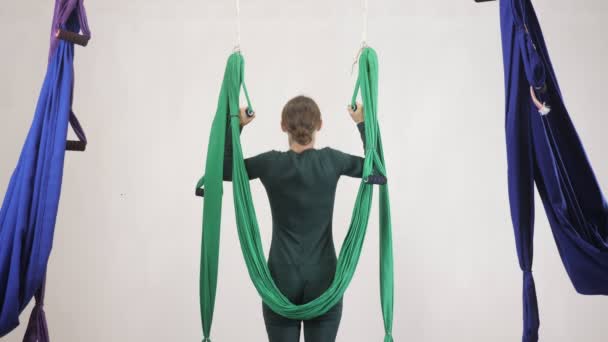 Mujer joven caucásica haciendo ejercicios de yoga con mosca antigravedad en hamaca en estudio en interiores. Aeronave aérea volar entrenamiento entrenador de fitness. Tablón vertical al revés. Medita, armonía y concepto de serenidad — Vídeo de stock