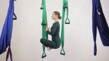 Genç Kafkas kadın kapalı Studio hamakta Anti yerçekimi sinek yoga egzersizleri yapma. Hava aero sinek fitness eğitmeni egzersiz. Lotus poz, derin derin düşünür, uyum ve huzur kavramı, yan görüntülemek 60 fps