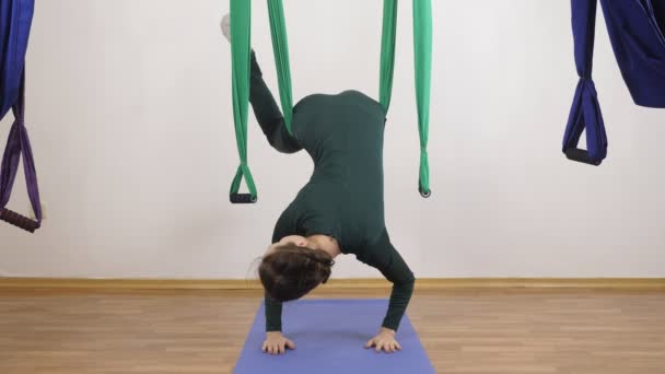 Unga kaukasiska kvinna att göra antigravitation flyga yogaövningar i hängmatta i studio inomhus. Aerial aero flyga fitness tränare träning. Handstående Pose, hängande. Mediterar, harmoni och lugn koncept — Stockvideo