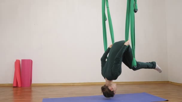 Jonge Kaukasische vrouw maken antigravity vliegen yoga oefeningen in hangmat in studio binnenshuis. Luchtfoto aero vliegen fitness trainer training. Verticale plank ondersteboven. Mediteert, harmonie en rust concept — Stockvideo