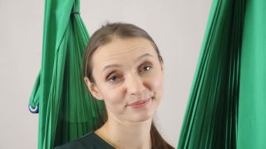 Genç güzel sinek yoga Koç portresi şüpheci bakar ve gülümser. Hava aero sinek fitness eğitmeni egzersiz. Derin derin düşünür, uyum ve huzur kavramı, yakın çekim, portret 60 fps