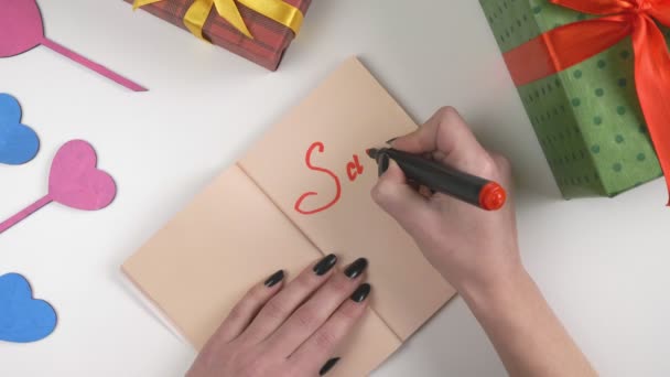 De dag van Valentijnskaarten, illustratie, dames hand schrijft in een donker bruin notebook, verkoop 50 procent korting op 60 fps — Stockvideo