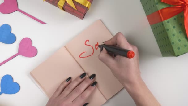 Día de San Valentín, ilustración, la mano de las mujeres escribe en un cuaderno de color marrón oscuro, la venta de 60 por ciento de descuento 60 fps — Vídeo de stock