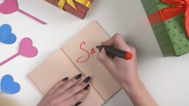 Día de San Valentín, ilustración, las mujeres mano escribe en un cuaderno de color marrón oscuro, venta 70 por ciento de descuento. 60 fps — Vídeo de stock