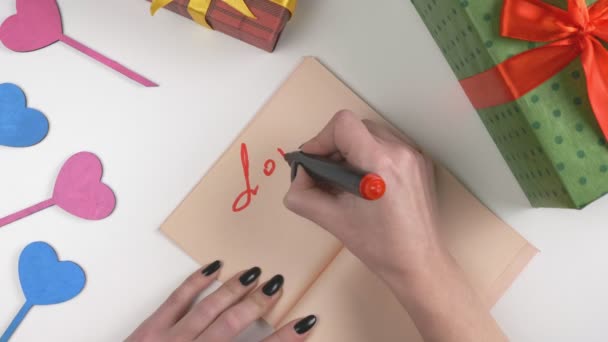 Día de San Valentín, ilustración, la mano de las mujeres escribe en un cuaderno marrón oscuro, El amor está en el aire 60 fps — Vídeos de Stock