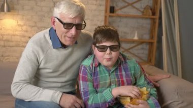 Dede ve torunu kanepede oturan ve 3d gözlük, 3d bir filmde konuşma, dans, Tv izlerken cipsi, yemek, göster. Ev konfor, Aile İdil, rahatlık kavramı, farkı