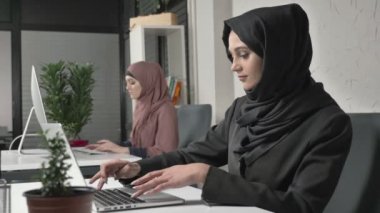 İki Müslüman kız ofiste, hijabs çalışmalarında yazın klavye, ekrana bak. Office, iş, iş, kadın, kavram. 60 fps