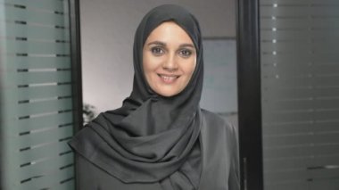 Elini bir jesti tebrik, Merhaba, Merhaba ofiste sallayarak bir hijab genç bir Arap kız. 60 fps