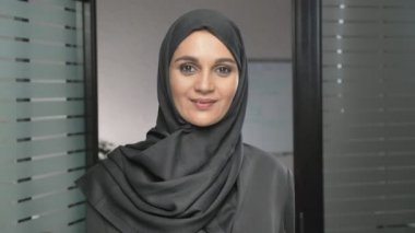 Elini bir jesti tebrik, Merhaba, Merhaba ofiste sallayarak bir hijab genç bir Arap kız. 60 fps