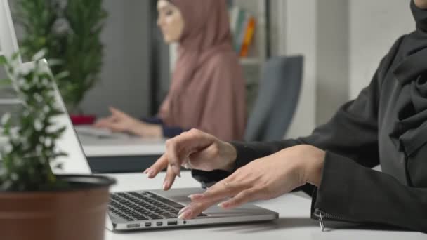 Tangan wanita mengetik di keyboard, close-up. Gadis berhijab merah muda di latar belakang. Kantor, bisnis, pekerjaan, wanita, konsep. Arab, Islam, hijab, agama, 60 fps — Stok Video