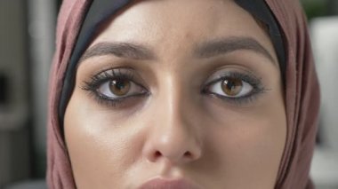 Genç güzel üzgün kız pembe hijab ve kameraya bakıyor. Portre, kadın gözleri kadar 60 fps kapatın.