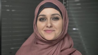 Gülümseyen ve kameraya bakarak pembe hijab genç güzel kız. Portre, 60 fps yakından