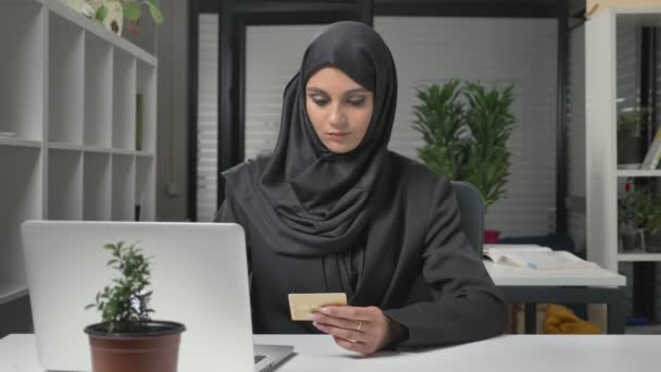 年轻漂亮的女孩在黑色头巾使购买在互联网上从笔记本电脑。信用卡。60 fps — 图库视频影像