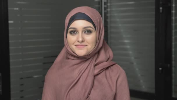 Молодая красивая девушка в розовом хиджабе улыбается и смотрит в камеру. Портрет 60 кадров в секунду — стоковое видео