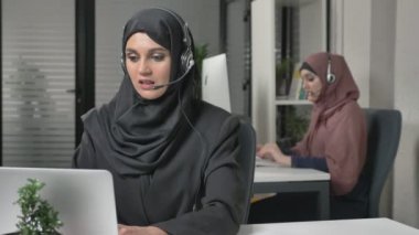 Kulaklık ile siyah Tesettür genç kız güzel bir çağrı merkezi cevaplar. Arap kadınları ofiste. Kavramı 60 fps