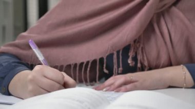 Güzel bir genç kız bir nokta ve pembe bir hijab Arapça olarak yazmak olacaktır. Tükenmez kalem. Arap kadınları ofiste 60 fps