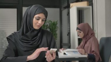 Siyah Tesettür genç güzel kızı ofiste smartphone kullanır. Arap kadınları ofiste 60 fps