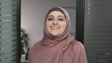 Genç mutlu Arap kız pembe hijab gülüyor. Kameraya, görünüyor portre. 60 fps