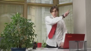 Genç adam bir takım elbise dansları ofiste, komik yüz yapıyor, aptallar, sevinir. Office kavramında işe 60 fps