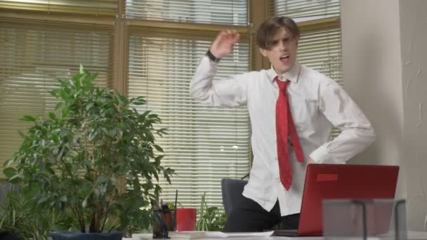 Jonge man in een pak dansen in het kantoor, zijn jas opstijgt maakt grappige gezichten, dwazen rond, verheugt zich. Werken in het office concept, 60 fps — Stockvideo