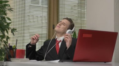 Ofiste, kulaklıklar, müzik dinleme dans elbiseli genç adam komik yüz yapıyor, aptallar, sevinir. Office kavramında işe 60 fps