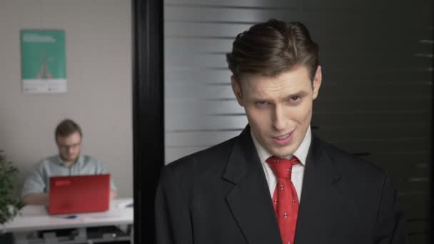 Young successful man in a suit shows Yes by shaking head. Man works on a computer in the background. 60 fps — Stock Video