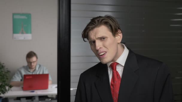 Giovane uomo di successo in giacca e cravatta, disgustoso. L'uomo lavora su un computer in background. 60 fps — Video Stock
