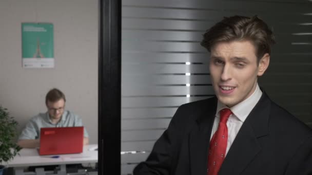 Yas by shaking head from successful businessman in suit, Yes by shaking head and pointing finger at the camera. Man works on a computer in the background. 60 fps — Stock Video