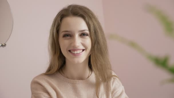 Jovem menina branca bonita sorrindo e olhando para a câmera. Retrato, close-up 60 fps — Vídeo de Stock