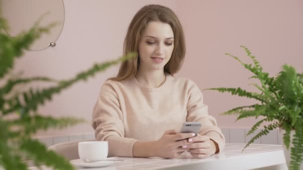 Mujer usando smartphone en cafetería bebiendo café sonriendo y mensajes de texto en el teléfono móvil internet, comunicación y concepto de tecnología 60 fps — Vídeos de Stock