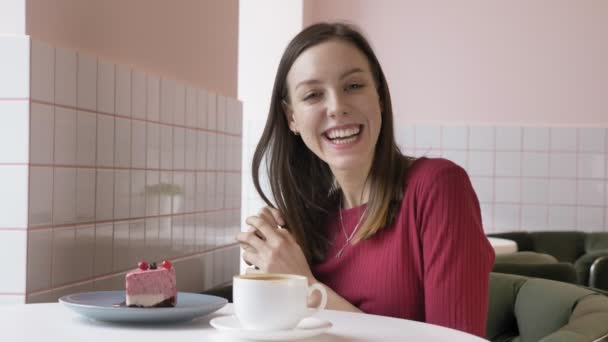 Młoda piękna dziewczyna brunetka uśmiechając się i patrząc na kamery w kawiarni, naturalny portret. 60 fps — Wideo stockowe